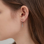 Feather Dangle Hoops in silver on ear