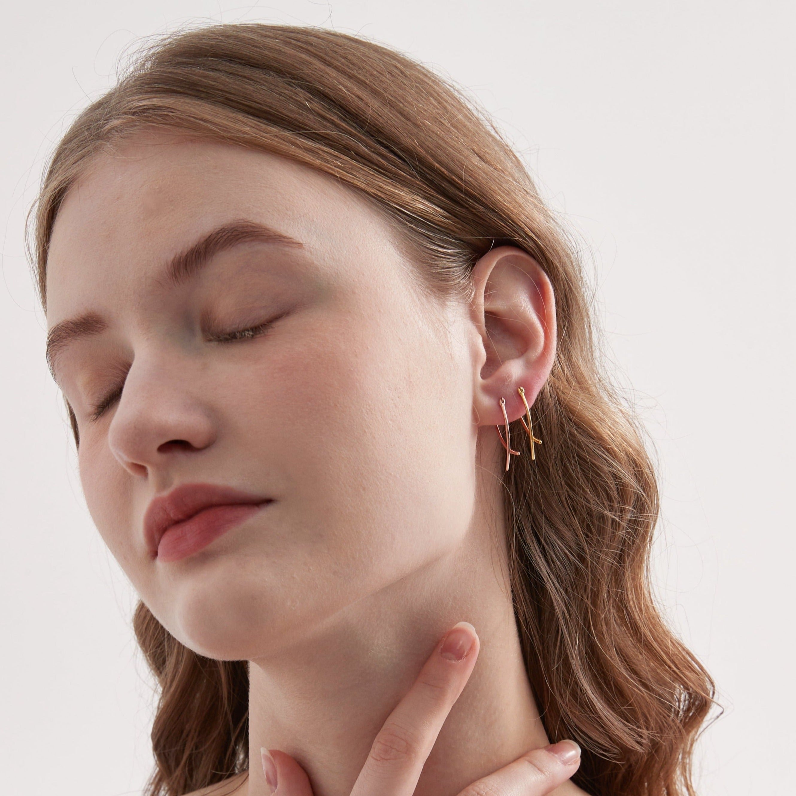 Geometric Cross Hoops in gold and rose gold on ear