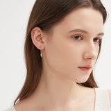 Feather Dangle Hoops in gold on ear