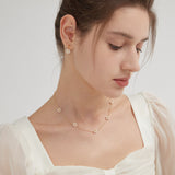 STMG Pearl Daisy Necklace in gold on neck with matching earrings on ear